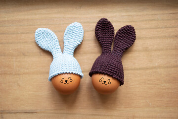 Crocheted Easter eggs with bunny ears on a wooden table. Soft focus