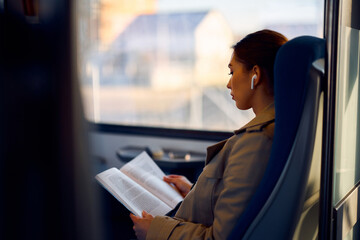 Young female passenger reads book while traveling by train. © Drazen