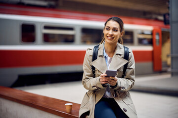 Happy tourist uses her mobile phone while waiting for train at subway.