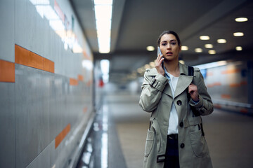 Young woman talking on monile phone at subway station.