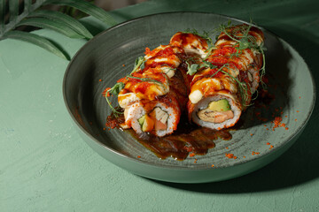 Unamaki with mango and red fish on a green plate among palm branches