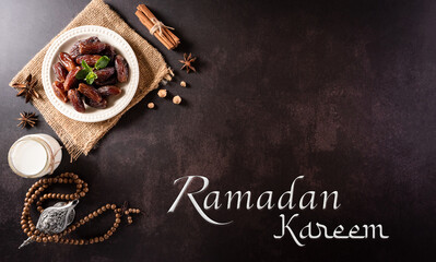 Table top view image of decoration Ramadan Kareem, dates fruit, aladdin lamp and rosary beads on dark stone background.