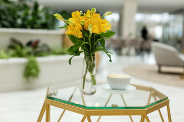 workplace, front view, coffee mug, bouquet of yellow flowers on the table. Green plants. Freshness. Creative concept.