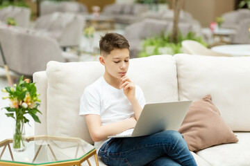 A teenage boy in school with an internet chat,  watching a webinar, taking notes, looking at a laptop, distance learning