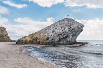 Man standing on top of a rock with his hands raised, in Cabo de Gata National Park,South of Spain.