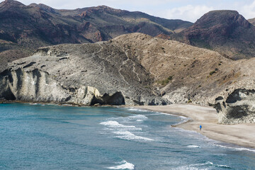 High angle view of a lonely man walking on a virgin beach.
