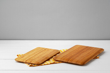 Wooden cutting board on cotton napkin on white wooden table