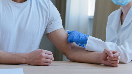 Close-up unrecognizable nurse doctor in medical coat and latex gloves giving injection in shoulder...