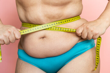 Measure female waist with tape closeup, folds on stomach, loose skin, fat and cellulite. Naked...