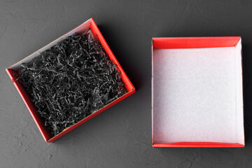 Open red paper box with tinsel on black background