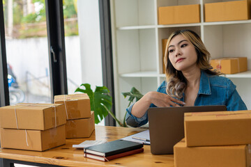 Naklejka premium Young Business Owners Work from Home Online Business Ideas Startup Small Business SME uses laptops to receive and check orders to prepare boxes for shipping products. Sales