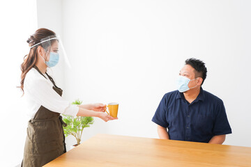 コロナウイルスの予防を徹底するカフェスタッフ