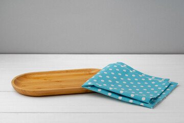 Wooden cutting board on cotton napkin on white wooden table