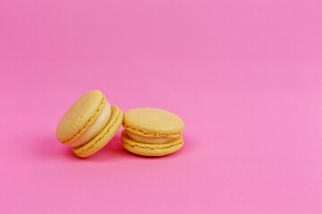 Colored yellow macaroons or macarons in pastel tones on a pink background with a place for writing and cutting. Minimalism.