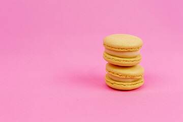Colored yellow macaroons  on a pink background with a place for writing and cutting. Minimalism.