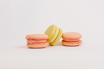 Multicolored macaroons on a solid white background with a place for writing and cutting. Minimalism. Yellow, orange, even. Beautiful cakes. Postcard.