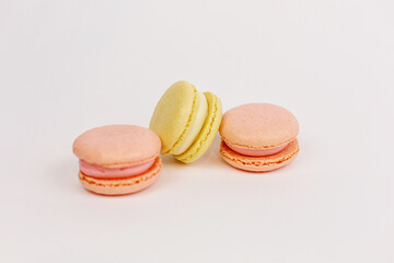 Multicolored macaroons on a solid white background with a place for writing and cutting. Minimalism. Yellow, orange, even. Beautiful cakes. Postcard.