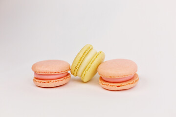 Multicolored macaroons on a solid white background with a place for writing and cutting. Minimalism. Yellow, orange, even. Beautiful cakes. Postcard.