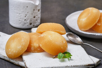 Several palm sugar cakes made from palm tree sap on a kitchen boards with a mint, spoon and jug....
