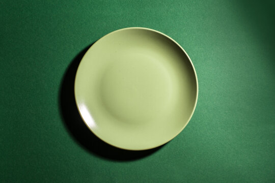 Green empty plate on green background