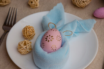 Easter decoration. Easter eggs on the table decorated with a napkin under the muzzle of a rabbit.