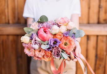 Very nice young woman holding big and beautiful bouquet of fresh peony, roses, eustoma, eucalyptus, in purple and peach colors, cropped photo, bouquet close up - 497292760