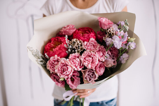 Very nice young woman holding big and beautiful bouquet of fresh roses, peony, chamellacium, matthiola in vivid pink colors, cropped photo, bouquet close up