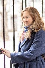 Portrait of a young woman with blonde hair in a blue coat. Spring