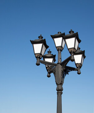An old lonely lantern against the blue sky. Vintage street lamp in the daytime.

