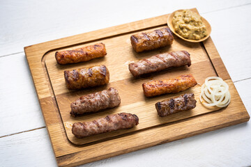 Gegrillte Cevapcici mit Zwiebelsenf auf einem Holzbrett