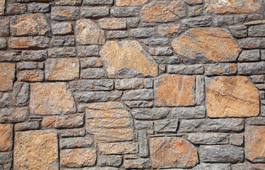 The stonewall background. Orange and grey stones were used on the stone wall. Close up.