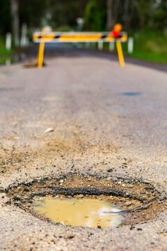 Muddy pot hole in gravel road closed because of flooding