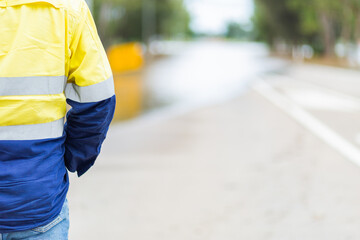 Council worker in high vis with copy space and floodwater over road