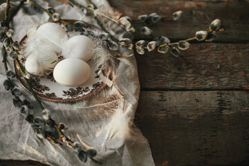 Natural egg in nest with feathers, vintage plate,  pussy willow branches and napkin on aged wood....
