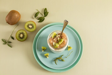 top view of a modern glass in the form of a can of energy nut smoothies made of kiwi and banana on a ceramic plate and a beige background. detox menu.