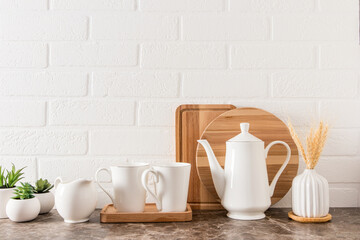 Fototapeta na wymiar kitchen modern background. white porcelain coffee pot, cups, milkman, indoor flowers in pots. front view.