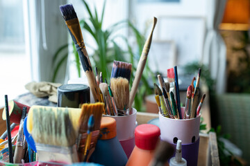 Fototapeta premium Close-up no people still life shot of various paintbrushes and liquids in bottles on windowsil in daylight