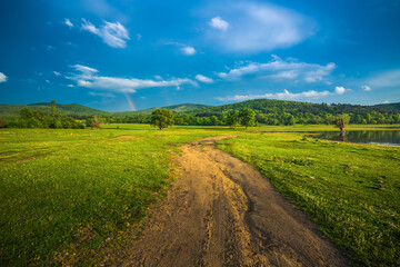 Rainbow over fields and trees on a farm on the edge of Lake