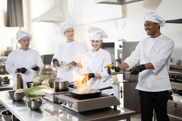 Multiracial team of professional cooks in uniform preparing meals for a restaurant in the kitchen....