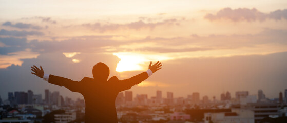 silhouette hand raised fist business man with sun lighting in morning. background city, success, grow up.