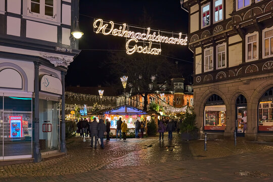 Goslar, Germany. The entrance to Christmas market at Market Square in night. The illuminated red historic guildhall Kaiserworth of 1494 is visible in the background.