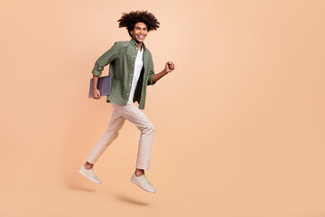 Fototapeta na wymiar Full length body size view of attractive cheery guy jumping holding laptop running work isolated on beige pastel color background