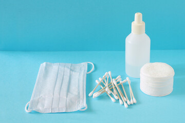 Cotton swabs and cotton pads for personal hygiene. Care product in a white bottle. White bamboo cotton buds on a blue background. Cotton buds can be used in medicine and cosmetology.