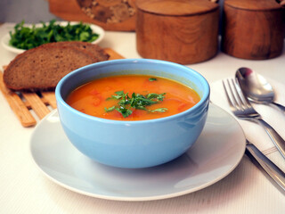 Orange pumpkin puree soup in a blue ceramic bowl. Rye bread. dinner serving