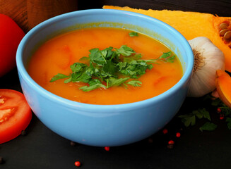A plate of Vedic pumpkin soup. Serving with fresh tomatoes and herbs. Close-up