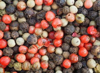 A mixture of different types of peppercorns. Background of pink, green, white, black peppers. Close-up