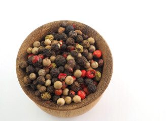 A mixture of peppercorns in a wooden bowl isolated on a white background. View from above