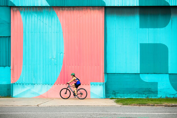 Female Cyclist Riding by a Colourful Wall