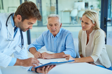 Obraz premium Lets take a closer look at your test results. Shot of a doctor discussing some paperwork with a senior patient and his daughter in a clinic.