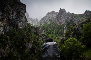 A backpacker stands looking at the sharp cliff edges